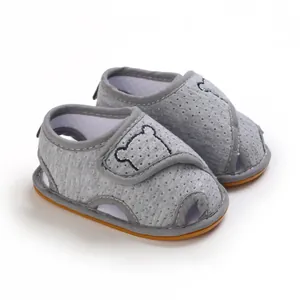 Detail of grey baby sandals featuring a cute bear silhouette and soft rubber soles