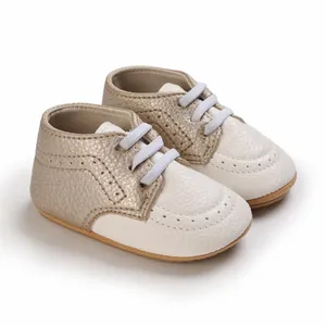 Close-up of soft-sole baby walking shoes in cream and gold with brogue details