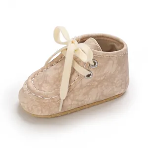 Nahaufnahme beiger Lauflernschuhe für Babys mit Marmorstruktur und cremefarbenen Schnüren