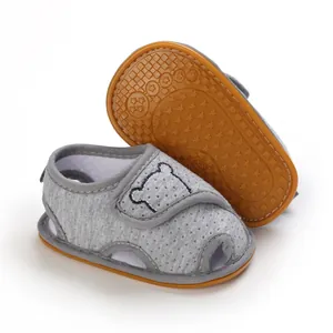 Close-up of grey baby sandals with soft rubber sole and cute bear embroidery detail.