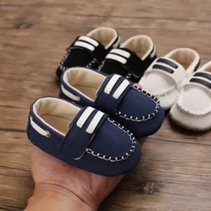 Weichsohlige Babylauflernschuhe in Blau, Schwarz und Weiß, handgehalten präsentiert