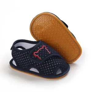 Close-up of navy blue polka dot baby sandals with soft rubber anti-slip sole detail.