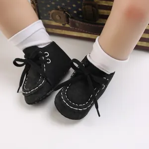 Detailaufnahme von schwarzen Baby-Lauflernschuhen mit weißen Nähten an Puppenfüßen