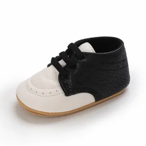 Macro detail of black and white faux leather baby shoes featuring a soft non-slip rubber sole