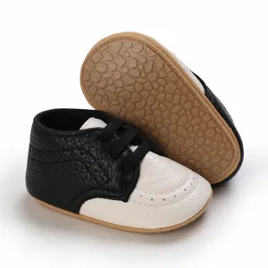 Macro view of black and white baby walking shoes with textured leather and soft rubber sole