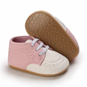 Close-up of pink and white infant pre-walker shoes with textured anti-slip rubber sole.