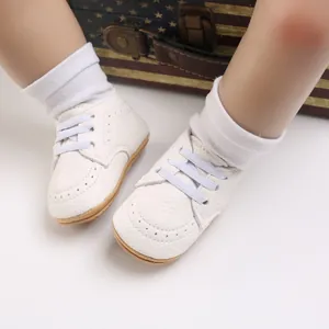 Close-up of white baby walking shoes with soft non-slip soles on doll feet for infants.