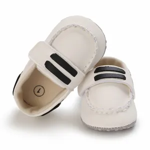 Vista superior detallada de zapatos blancos para bebés con rayas negras y cierre de velcro