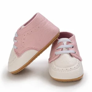 Close-up detail of pink and white baby walking shoes with soft non-slip rubber soles.