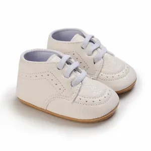 Detailed view of elegant white faux leather infant walking shoes with soft rubber soles