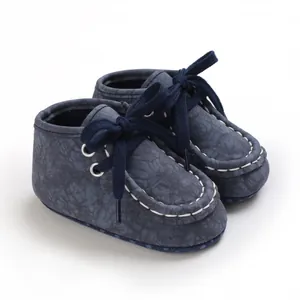 Detailansicht von dunkelblauen Babyschuhen mit weißen Nähten und marineblauen Schnürsenkeln