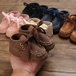 Nahaufnahme von braunen Baby-Lauflernschuhen aus Kunstleder, die zur Skalierung gehalten werden