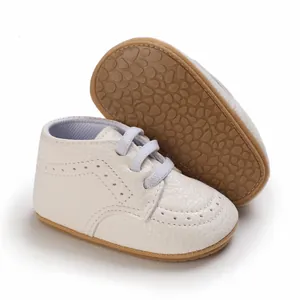 Detail of white infant baby walking shoes with soft non-slip rubber sole and brogue design