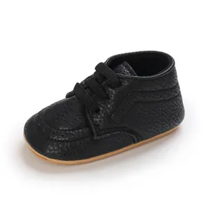 Detail of black textured faux leather baby pre-walker shoe with tan anti-slip sole