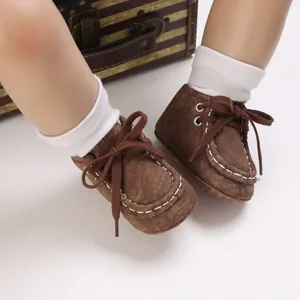 Makroansicht von braunen Babyschuhen mit weißen Nähten und Baumwollschnürsenkeln.