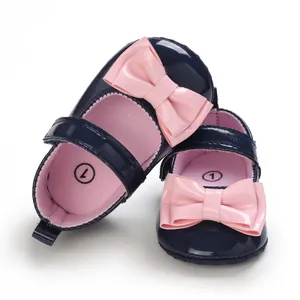 Detailansicht von marineblauen Babyschuhen für Mädchen mit großen rosa Lackschleifen