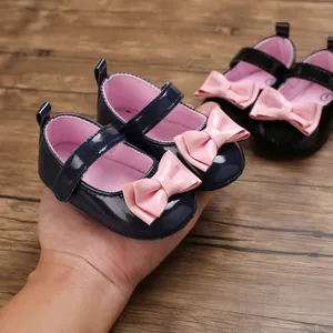 Detail von dunkelblauen Baby-Lauflernschuhen mit rosa Schleife.