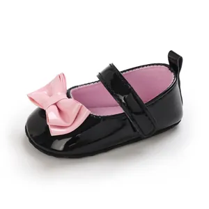 Detail schwarzer Lack-Lauflernschuhe für Babys mit großer rosa Schleife und weicher Sohle