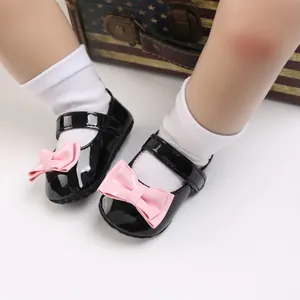 Nahaufnahme schwarzer Lack-Babyschuhe mit rosa Schleife und weicher Sohle