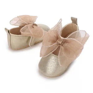 Detaillierte Makroansicht goldener Babyschuhe mit eleganten Schleifen aus Mesh-Gewebe