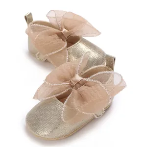 Detaillierte Nahaufnahme goldener Baby-Prinzessin-Schuhe mit einer großen Netzschleife