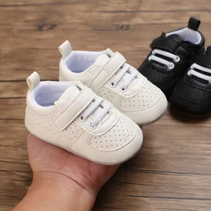 Detalle de zapatos de bebé blancos para caminar con suelas de goma suaves en mano