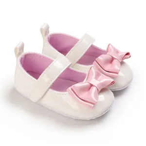 Detail von weißen Baby-Mary-Jane-Schuhen mit weicher Sohle und rosa Schleife