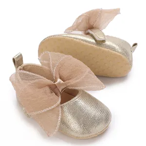 Detailansicht der goldenen glitzernden Lauflernschuhe mit großer dekorativer Tüllschleife