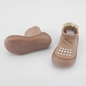Vista detallada de zapatos de calcetín para bebé marrones con punto transpirable y suela goma.
