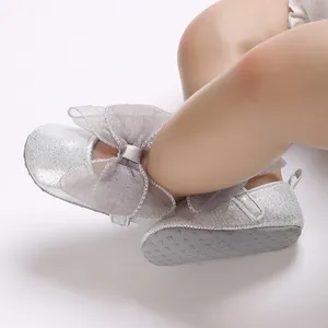 Detail von silbernen Glitzer-Babyschuhen mit grauer Netzschleife und rutschfester Sohle