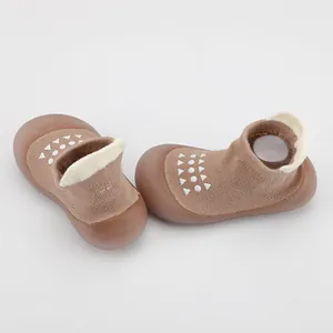 Detalle de zapatos calcetín marrones para bebé con suelas de goma suaves antideslizantes