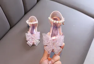 Primer plano de zapatos de princesa rosas para niña con lazo de pedrería y perlas