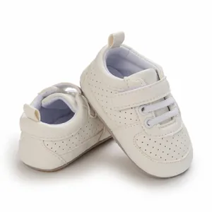 Primer plano de zapatos de bebé crema suaves con detalles perforados y tira de velcro.