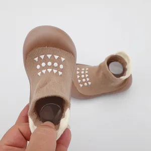 Primer plano de los zapatos de calcetín suaves marrón para bebé con patrones