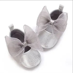 Detailansicht silberner glitzernder Babyschuhe mit großen, dekorativen Netzschleifen.
