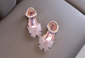 Detalle de zapatos de princesa rosas para niñas con lazo de malla y perlas