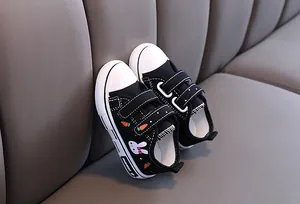 Vue détaillée de chaussures en toile noire pour enfants avec broderie lapin et carotte