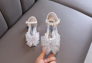 Detalle de zapatos de princesa plateados para niña con lazo de diamantes y perlas