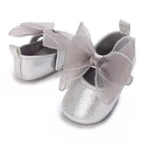 Detail von silbernen Glitzer-Babyschuhen mit einer großen, durchsichtigen grauen Schleife