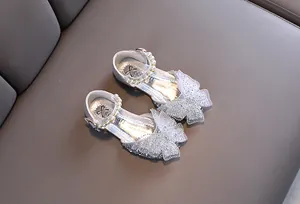 Primer plano de zapatos de princesa plateados para niña con lazo de mariposa brillante