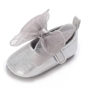 Nahaufnahme silberner Glitzer-Lauflernschuh mit großer grauer Schleife.