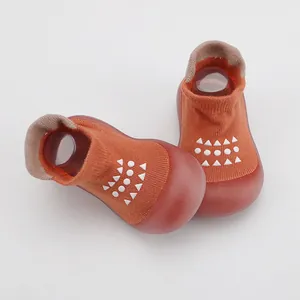 Vista detallada de zapatos de bebé naranja con suela de goma blanda y tejido de punto.