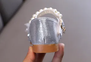 Vista detallada de zapatos de princesa plateados para niñas con correa de perlas