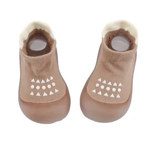 Primer plano de zapatos calcetín marrones para bebé con patrones geométricos blancos antideslizantes