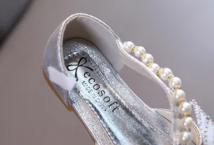 Primer plano de zapato de princesa plateado para niña con correa de perlas y logo