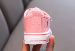 Gros plan sur le talon d'une chaussure en toile rose pour enfant avec broderie carotte