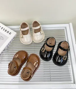 Vista de detalle de los zapatos de cuero para niñas en colores crema, negro y marrón
