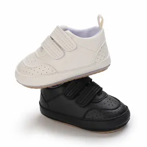 Dettaglio ravvicinato di scarpe da ginnastica per neonati in PU bianco e nero con suola morbida.