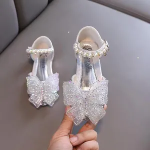 Zapatos de princesa plateados brillantes con elegantes lazos de mariposa y perlas