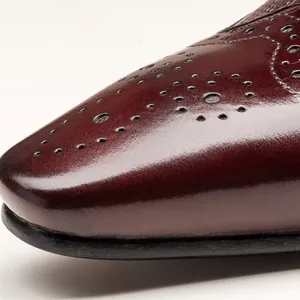 Détail macro d'une chaussure pour homme en cuir de veau bordeaux avec motifs richelieu